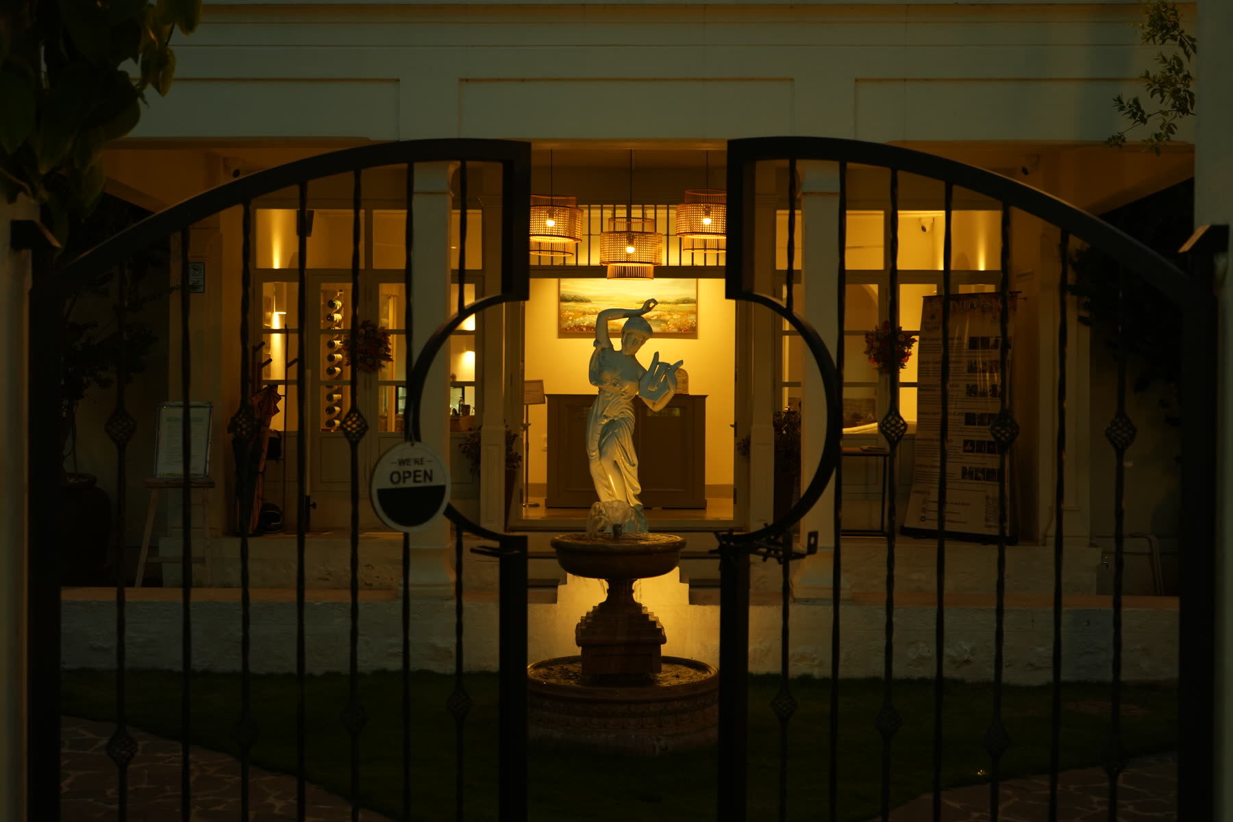 The lit wrought-iron gate and courtyard fountain at The Sorrento, Mysuru