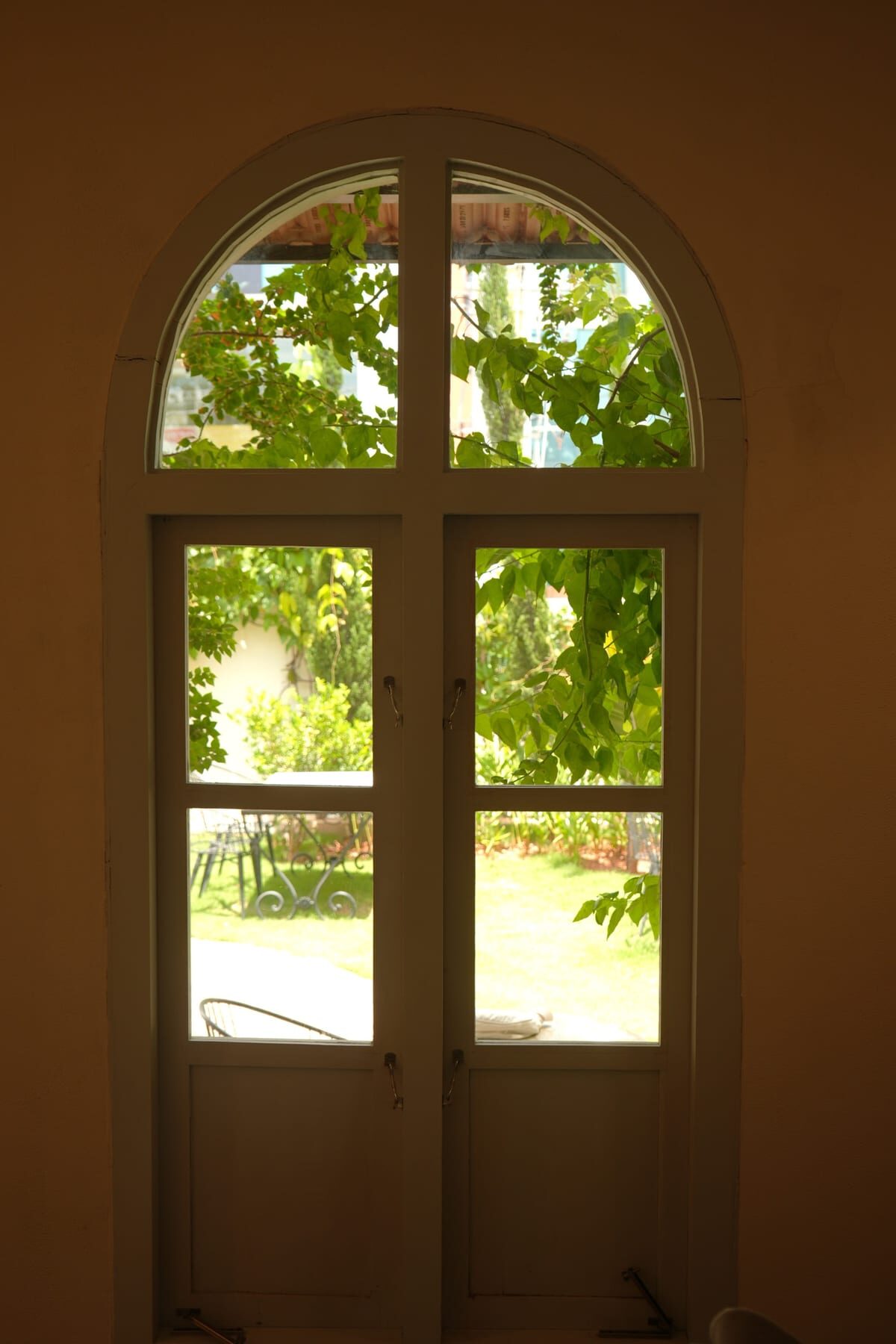 An arched villa window opening onto the green courtyard garden at The Sorrento, Mysuru